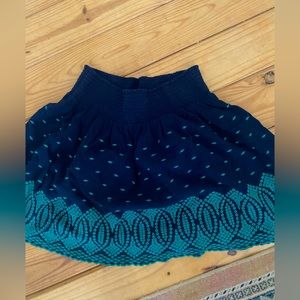 Navy smocked waist skirt with green embroidery detail.